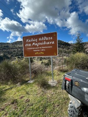 Πινακίδα από τα Μαγούλιανα με φόντο το βουνό Μαίναλο και το πίσω μέρος από ένα buggy